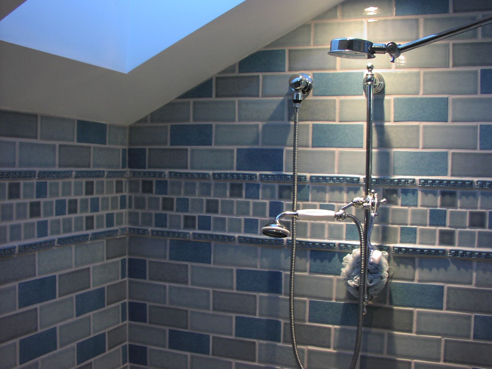 Regadera de doble cabezal en un baño con azulejo azul